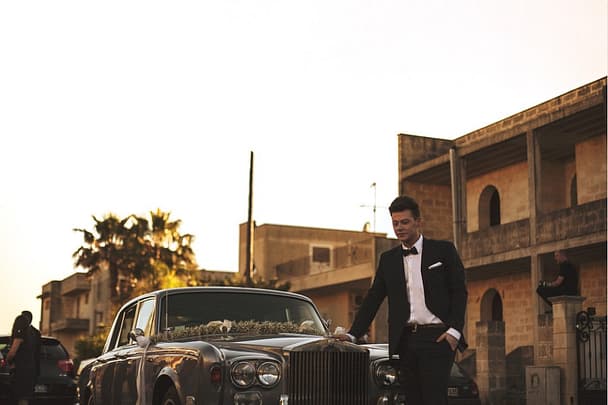 a groom standing in front of a limo