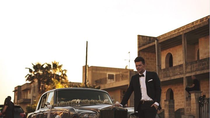a groom standing in front of a limo